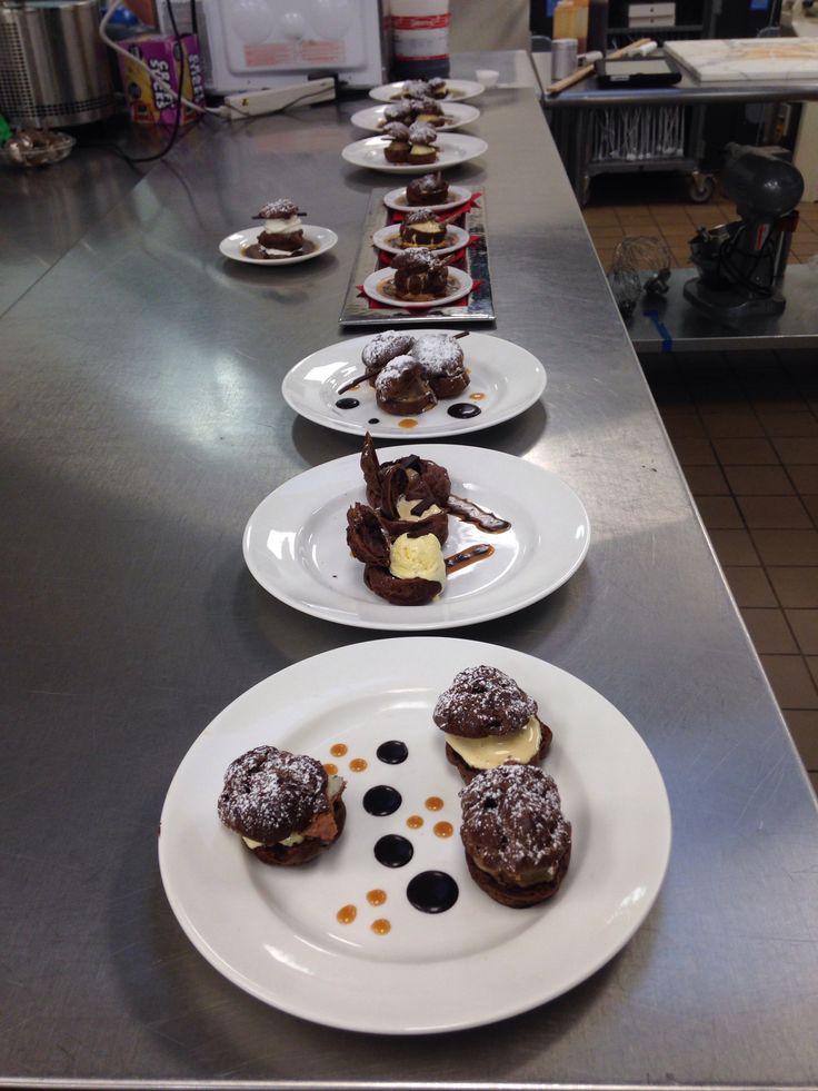 several desserts are lined up on plates in a line along the counter top at a restaurant