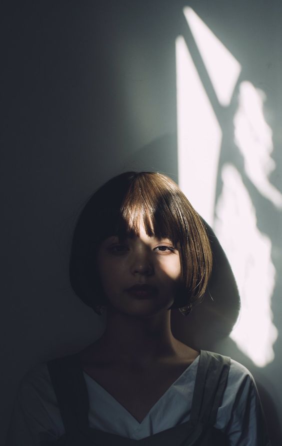 a woman standing in front of a window with her shadow on the wall