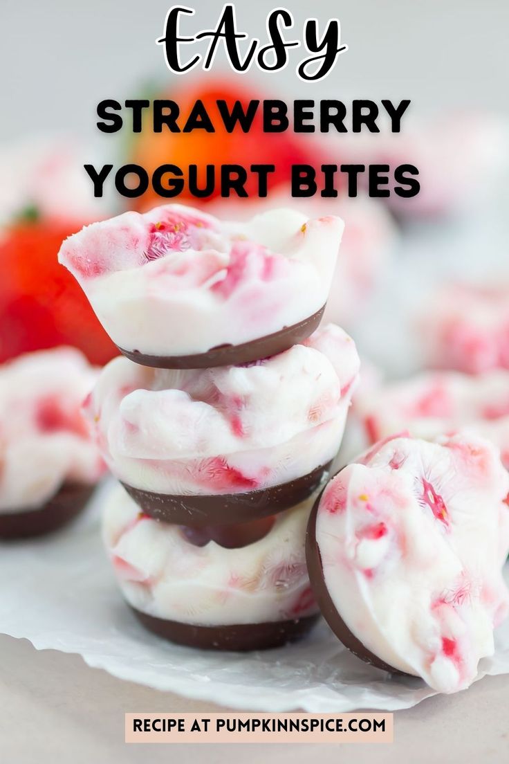 strawberry yogurt bites stacked on top of each other with strawberries in the background