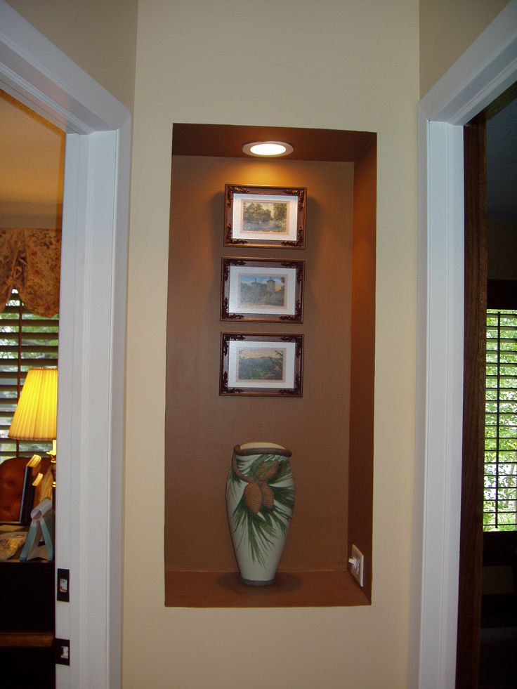 a vase sitting on top of a wooden shelf next to a window with shutters