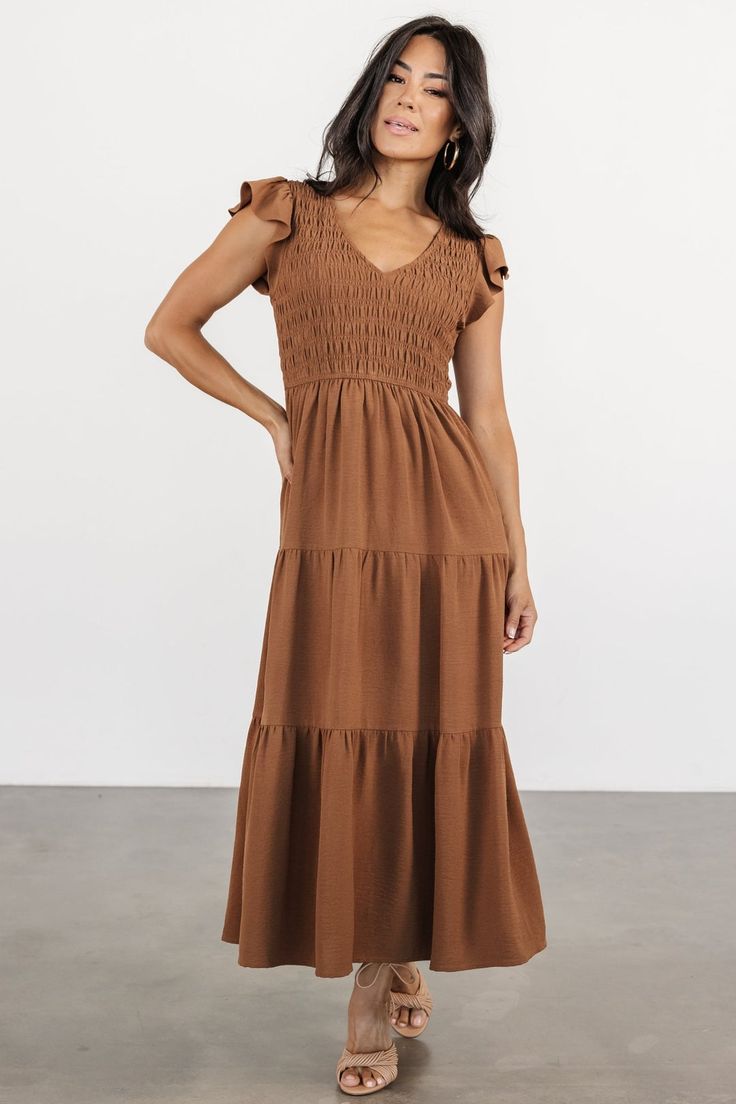 Introducing The Brandie, your new go-to choice for casual weekend brunch. With its warm medium brown hue, V-neckline, and cap-length flutter sleeves, this dress offers a relaxed yet stylish option, featuring a fully smocked bodice, natural waist, and midi-length skirt with three tiers for effortless charm. Brown V-neck Dress With Ruffle Hem, Brown Smocked Bodice Midi Dress For Brunch, Brown Smocked Bodice Dress For Brunch, Summer Brown Maxi Dress With Smocked Bodice, Brown Midi Dress With Smocked Bodice For Brunch, Brown Ruched Smocked Dress For Summer, Brown Smocked Back Dress For Brunch, Brown Smocked Back Dress For Summer, Brown Smocked Back Dress For Vacation