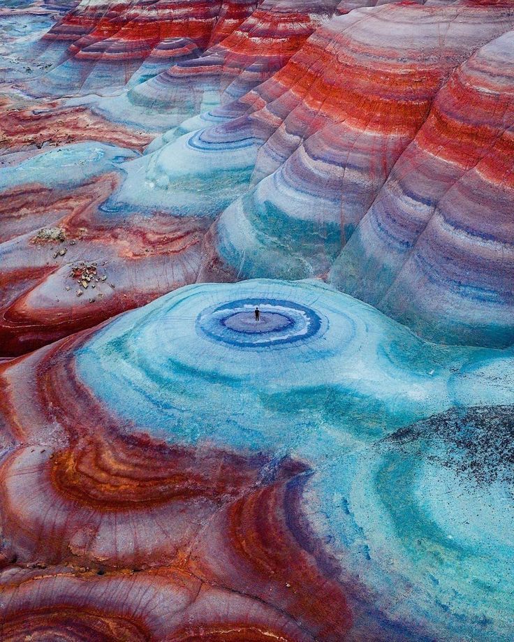 a man standing on top of a colorful rock formation