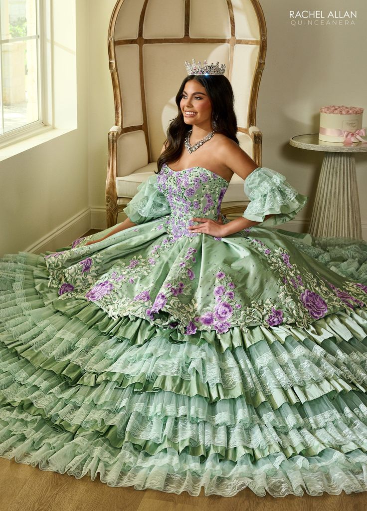 Make a grand entrance in this multicolored floral embroidered long strapless dress with A-line tiered lace skirt by Rachel Allan RQ5002. Introducing the ultimate dress of grace, elegance, and tradition! This enchanting taffeta ballgown has been meticulously crafted to make every quinceanera girl's dreams come true. With its captivating lace detail, dazzling applique and beading, and the added touch of detachable tulle sleeves, this dress is truly a masterpiece. Floral Tiered Lace Quinceanera Dre Floral Ballgown, Red Quinceanera Dresses, Black Ball Gown, Tulle Sleeves, Dresses Quinceanera, Dress Guide, Rachel Allan, Sweet 16 Dresses, Beaded Applique