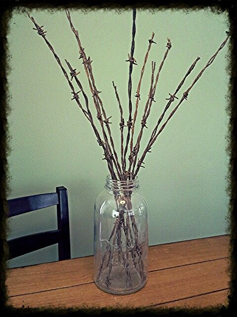 a glass vase filled with twigs on top of a wooden table