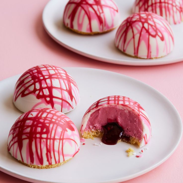 three desserts on white plates with red and white icing drizzled over them