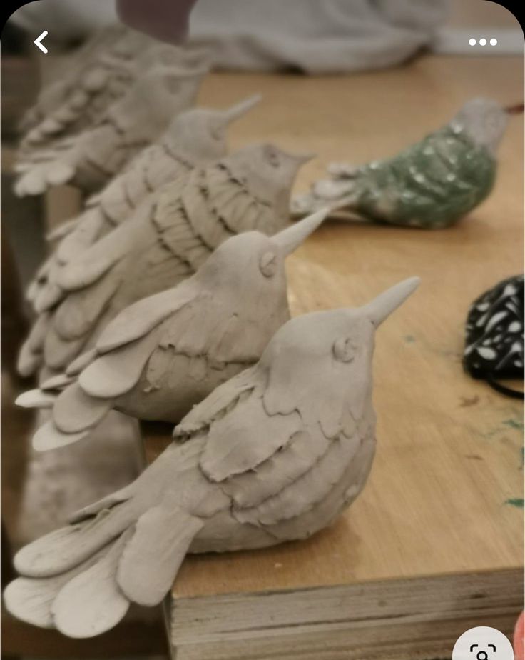 clay birds sitting on top of a wooden table