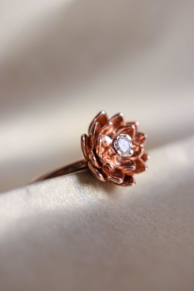 a rose shaped diamond ring sitting on top of a white cloth