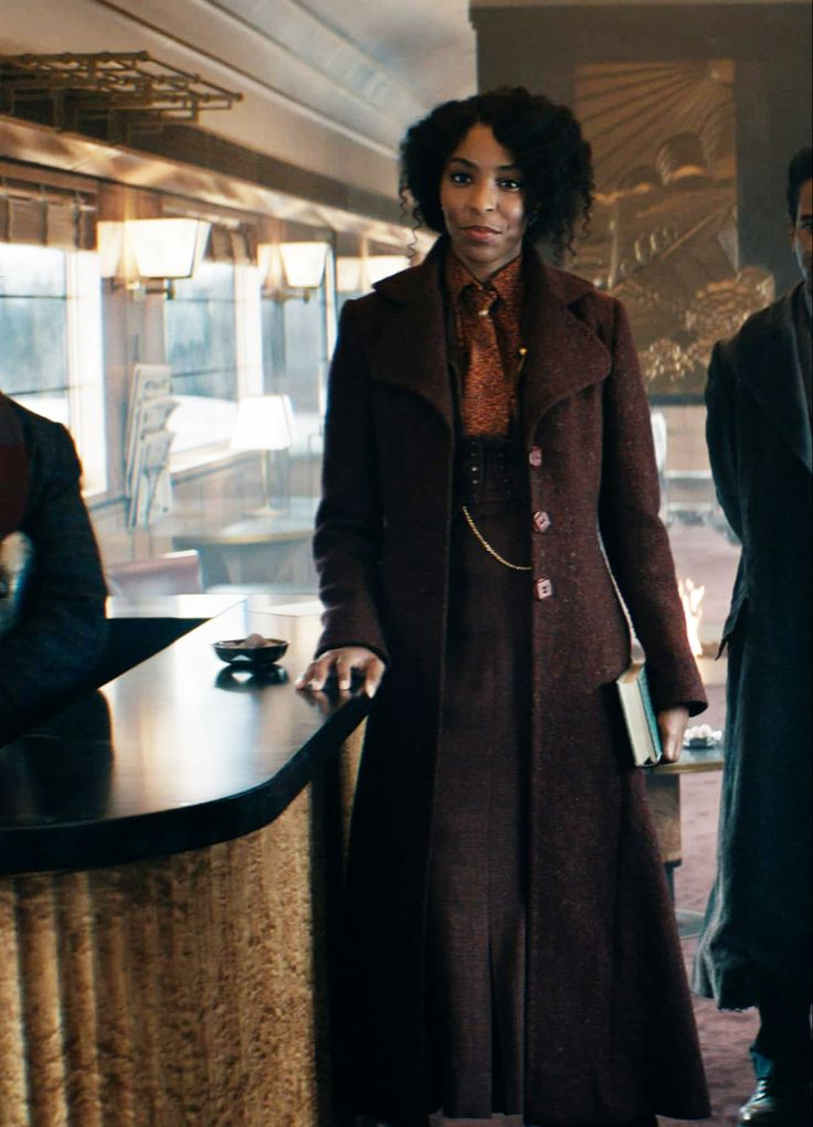 a woman standing in front of a counter next to two men wearing suit and tie