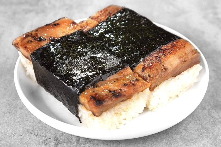 a white plate topped with rice covered in black sauce and meat on top of it