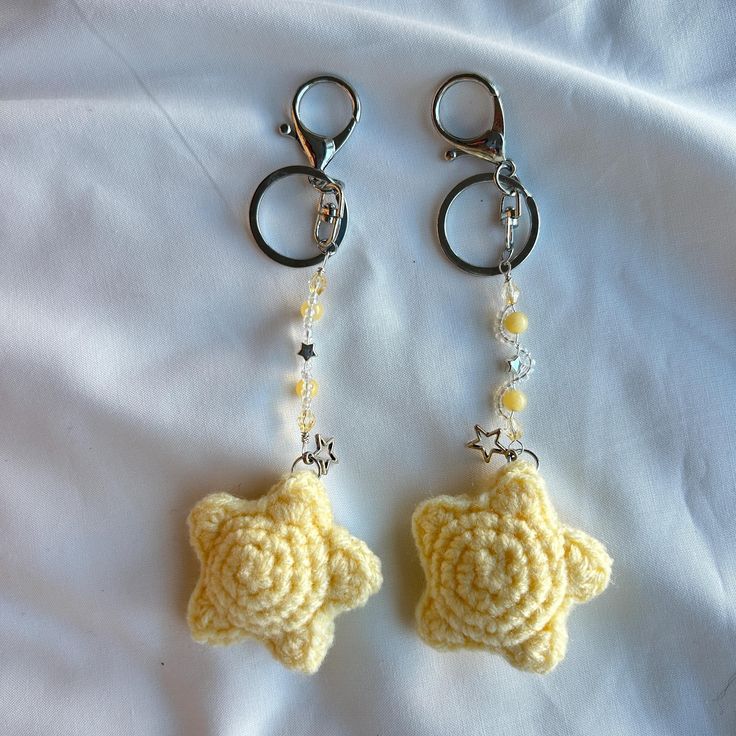 two crocheted star shaped key chains on top of a white sheet