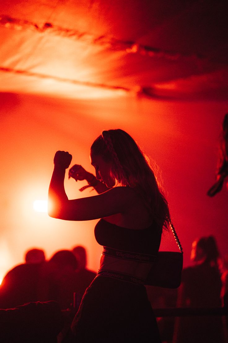 a woman standing on top of a stage with her arm in the air and arms raised