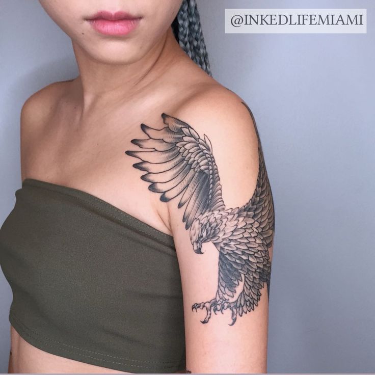 a woman with a bird tattoo on her arm and shoulder is looking at the camera