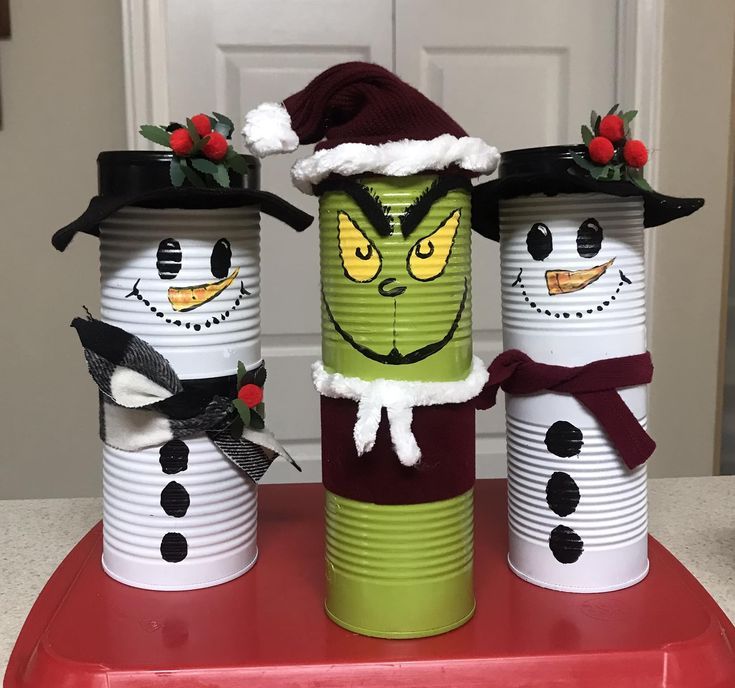 three tin can snowmen with hats and scarfs on top of a red tray