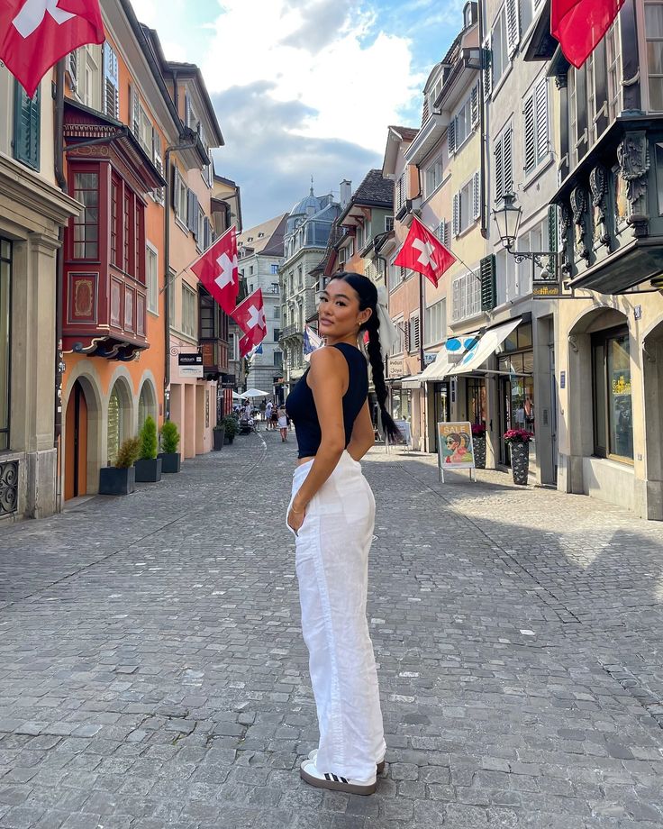 a woman standing in the middle of an empty street with canadian flags flying above her