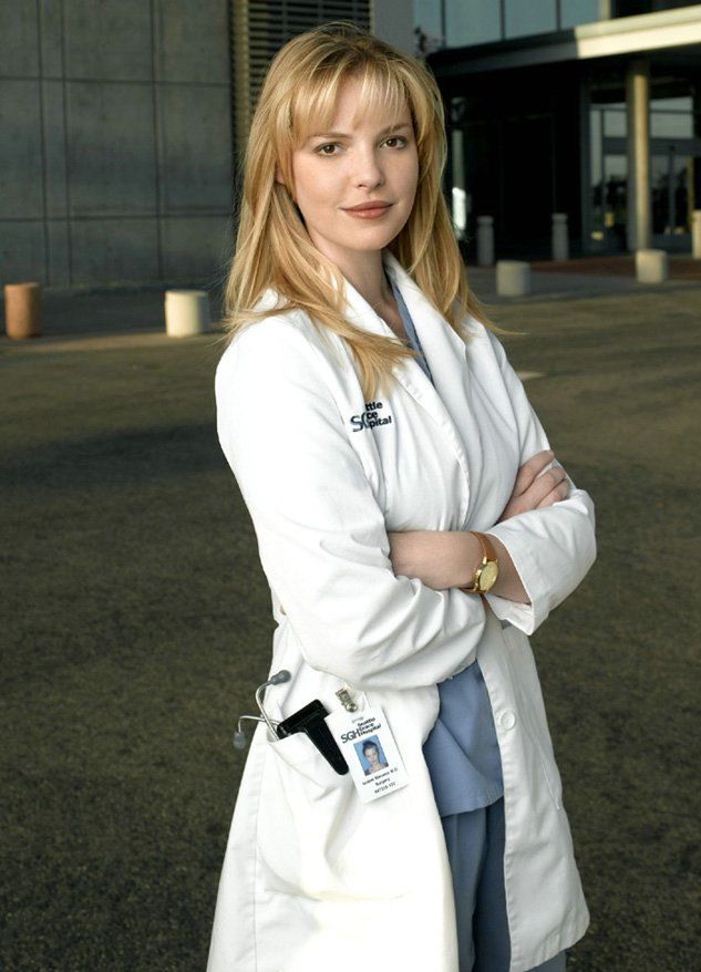 a woman standing in front of a building with her arms crossed and looking at the camera