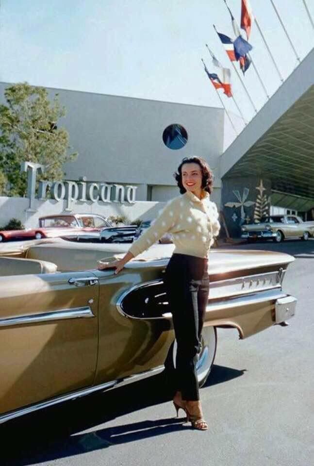 a woman standing next to a car in front of a building