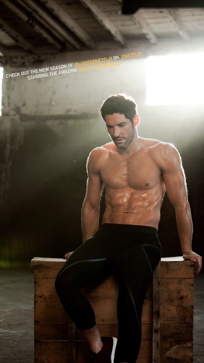 a shirtless man sitting on top of a wooden crate