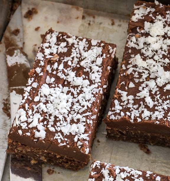 there are four pieces of chocolate cake on the baking sheet with coconut flakes all over them