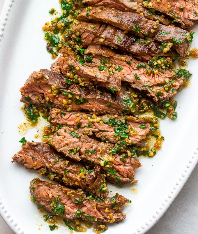 grilled steak with chimica sauce on a white platter, ready to be eaten