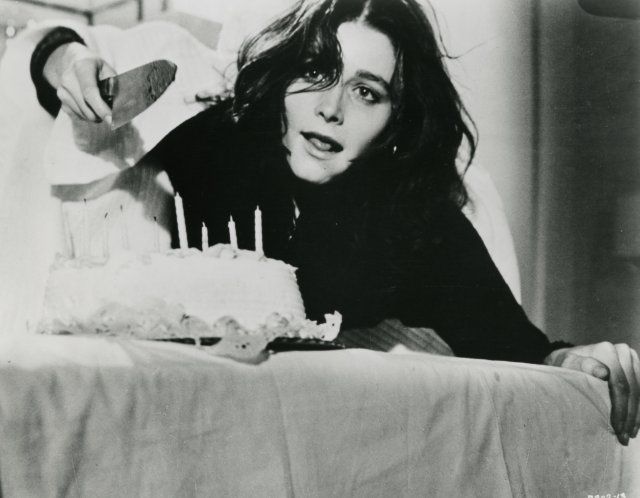 a woman leaning over a table with a cake in front of her