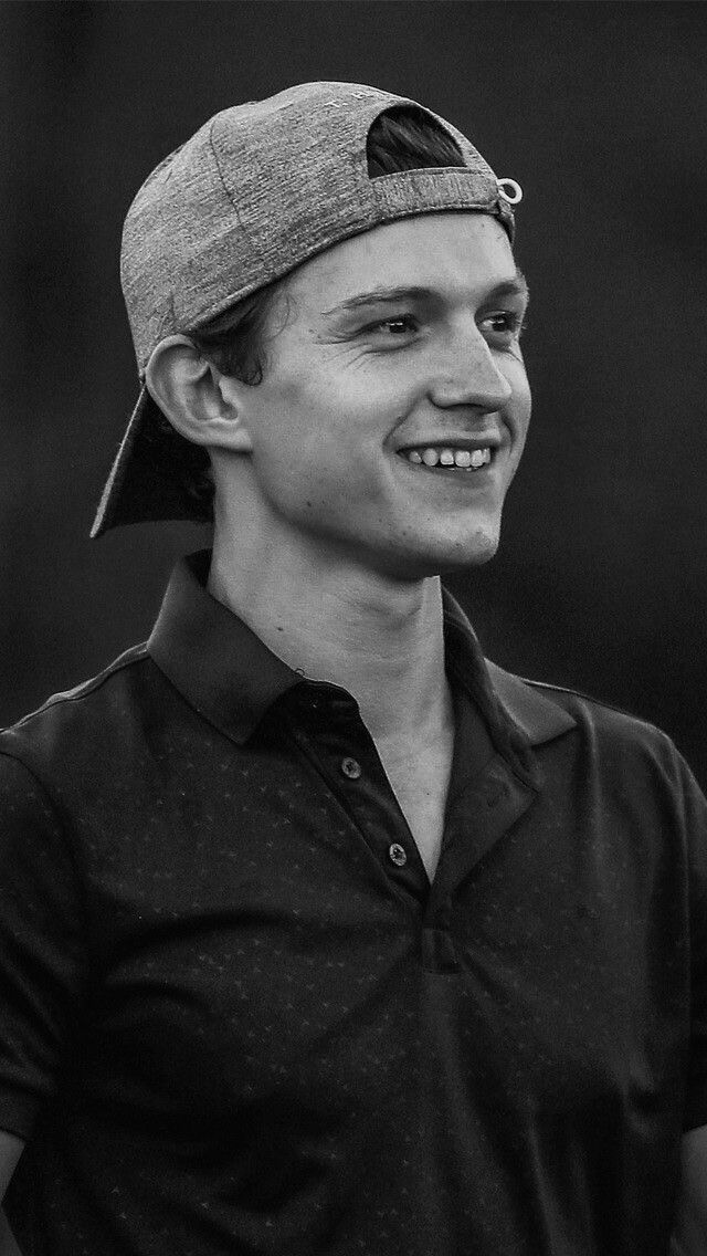 black and white photograph of a young man wearing a baseball cap smiling at the camera