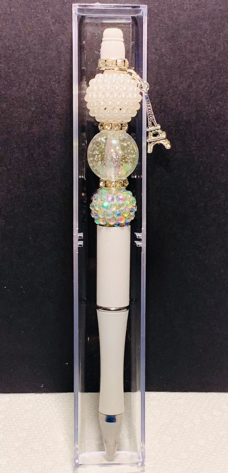 a white pen in a clear case with beads on the top and an attached keychain