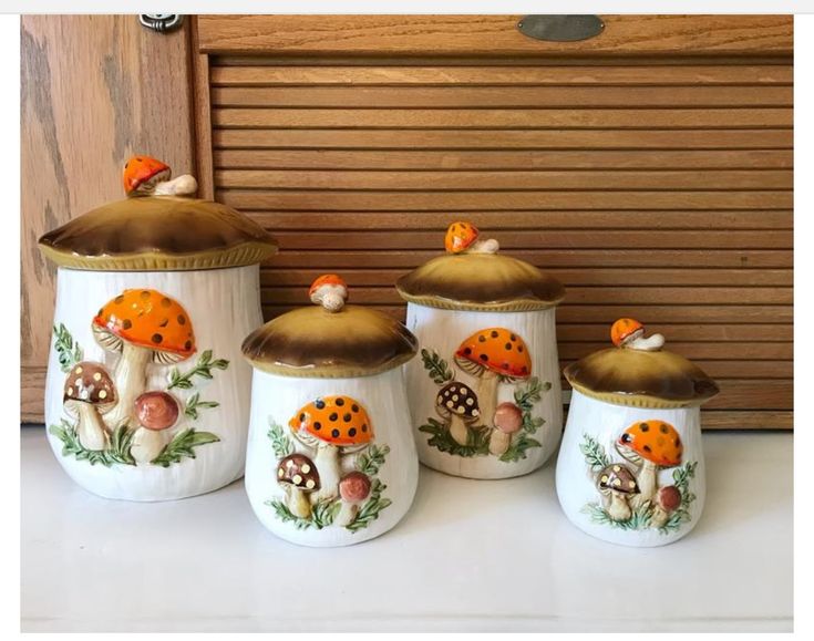 four ceramic canisters with mushrooms painted on them