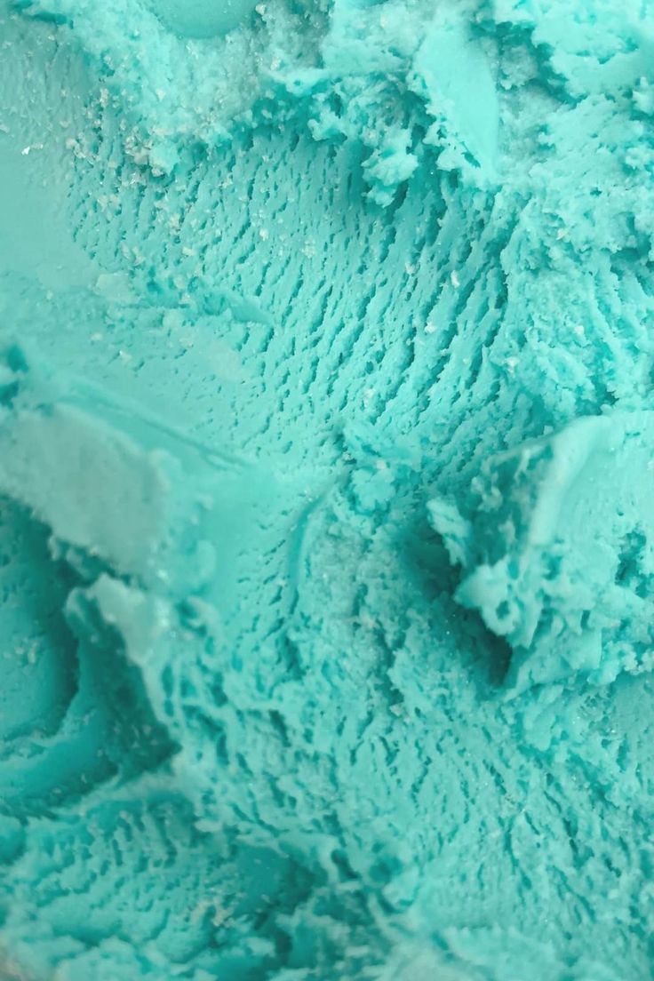 a bowl filled with blue ice cream sitting on top of a table