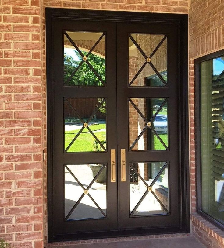 the front door to a home with glass panels on it and a brick wall behind it