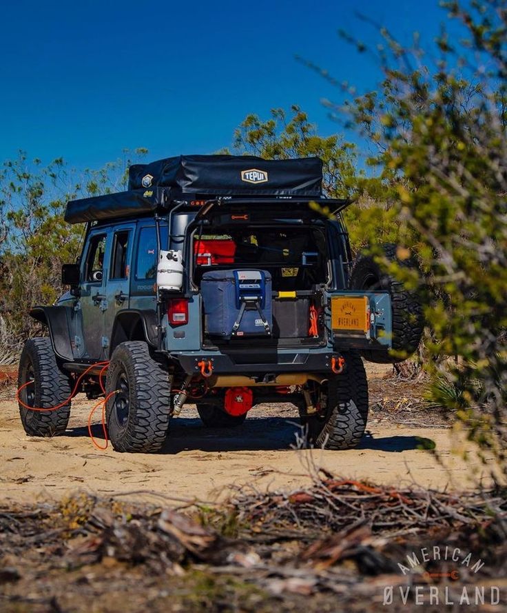 an off road vehicle parked on the side of a dirt road with trees in the background