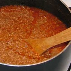 a wooden spoon in a pot filled with chili