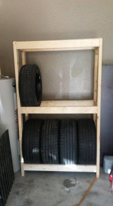 some tires are stacked on top of each other in a storage rack next to a water heater