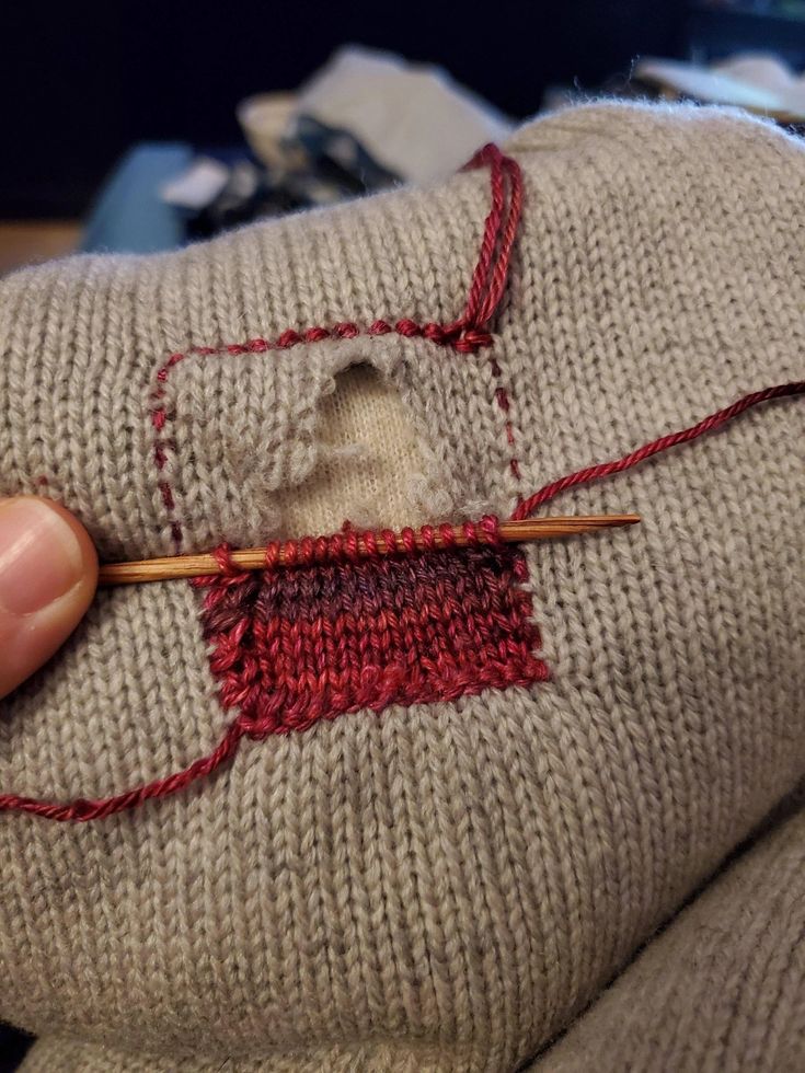 someone is stitching something on the sweater with a knitting needle in their left hand