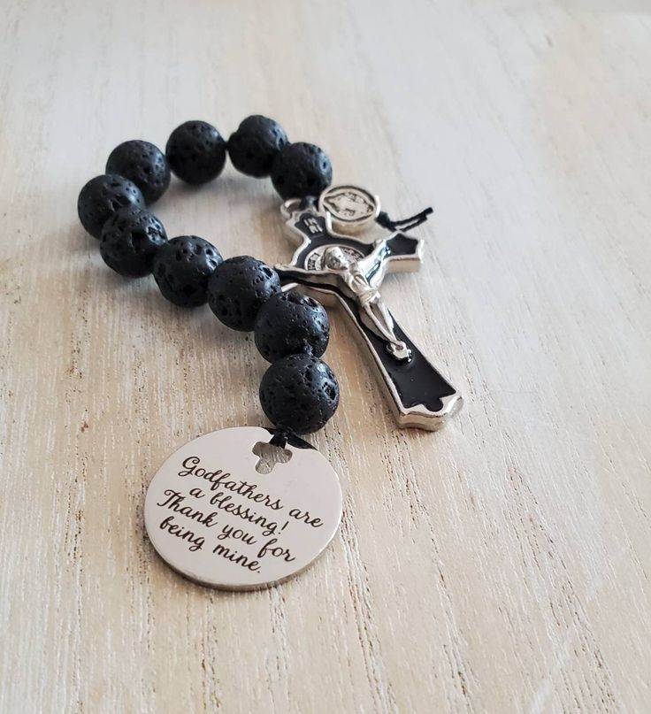 "\"Godfathers are a blessing, thank you for being mine\" This beautiful handmade rosary is the perfect proposal or thank you gift for a Godfather, even as a Christmas, birthday or Fathers day gift.  This handmade rosary is made using 10mm black lava stone beads. The beads are hand knotted using nylon thread.  The stainless steel charm is laser engraved and has a unique cross cutout. The cross is high quality silver tone metal and black enamel.  This rosary can be made in other gemstones as will arrive in a pouch ready to be gifted." Mother's Day Gift Rosary With 8mm Beads, Adjustable Rosary With Miraculous Medal Gift, Personalized Spiritual Rosary As Gift, Personalized Spiritual Rosary Gift, Spiritual Cross Rosary Bracelet For Gift, Spiritual Gift Rosary Bracelet With Cross, Spiritual Cross Rosary Bracelet Gift, Spiritual Rosary Bracelet With Cross Shape, Godfather Proposal