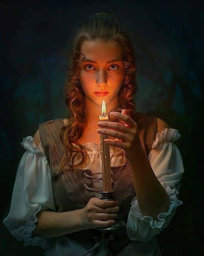 a woman holding a lit candle in her hands