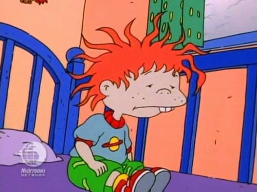 a kid with red hair sitting on a bed