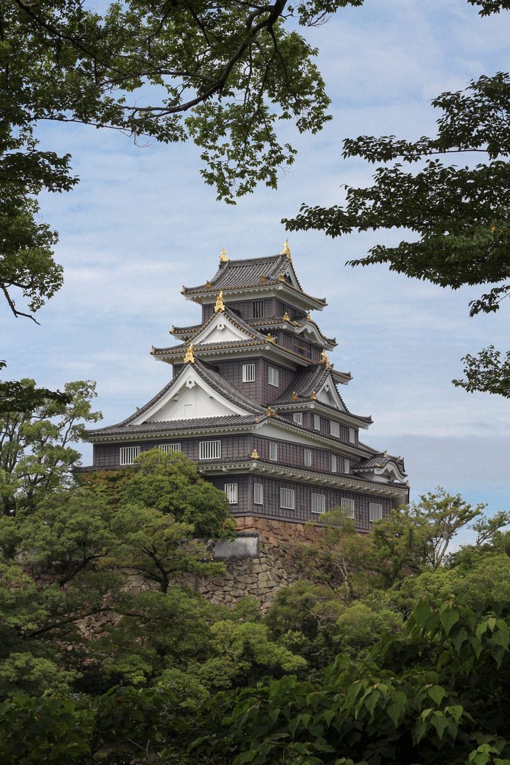 a tall building sitting on top of a lush green hillside next to trees and bushes