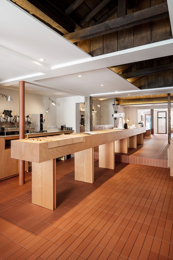 an empty room with wooden flooring and tables in the center, along with other furniture