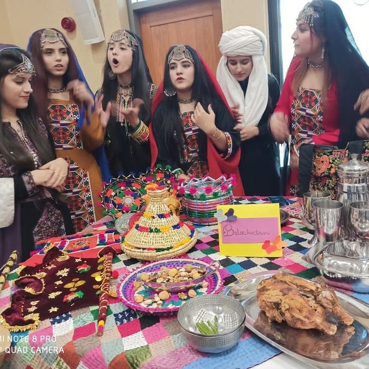 a group of young women standing around a table covered in food and desserts,