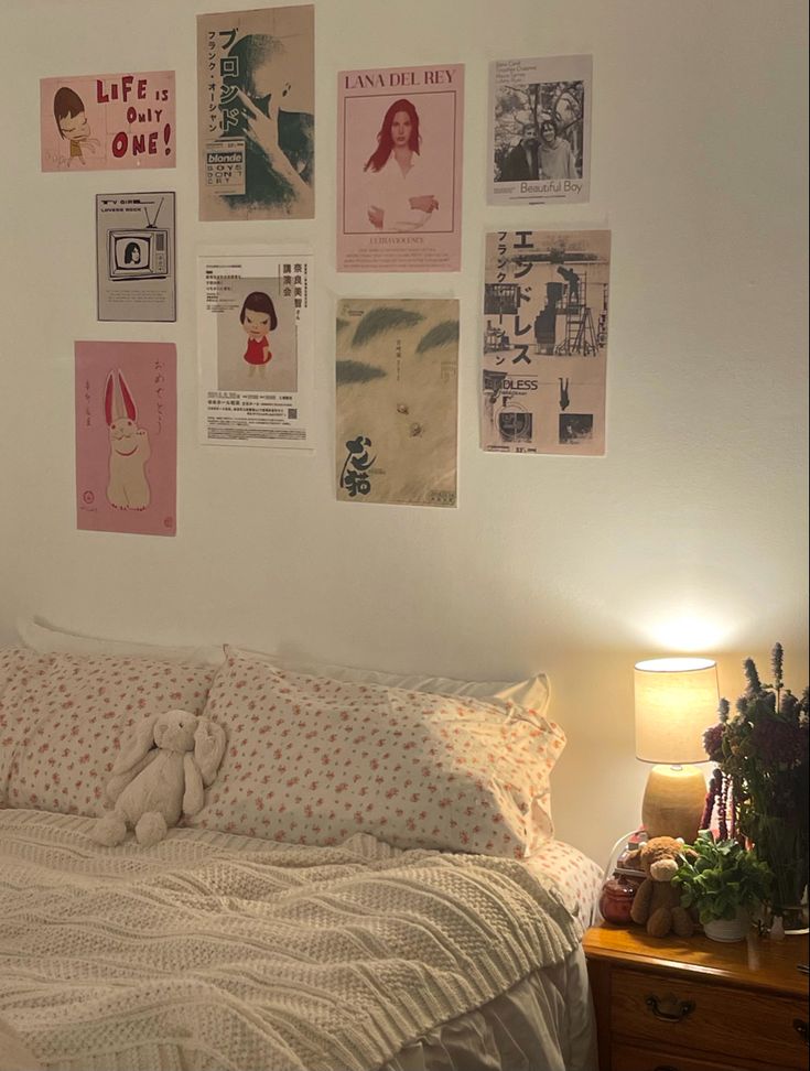 a bedroom with posters on the wall and a white bed in front of a wooden night stand