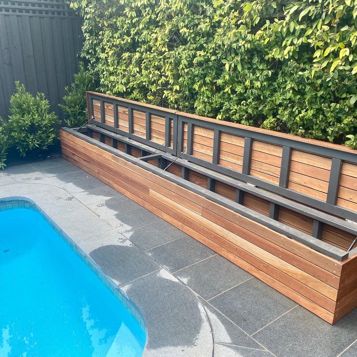 a wooden bench sitting next to a swimming pool