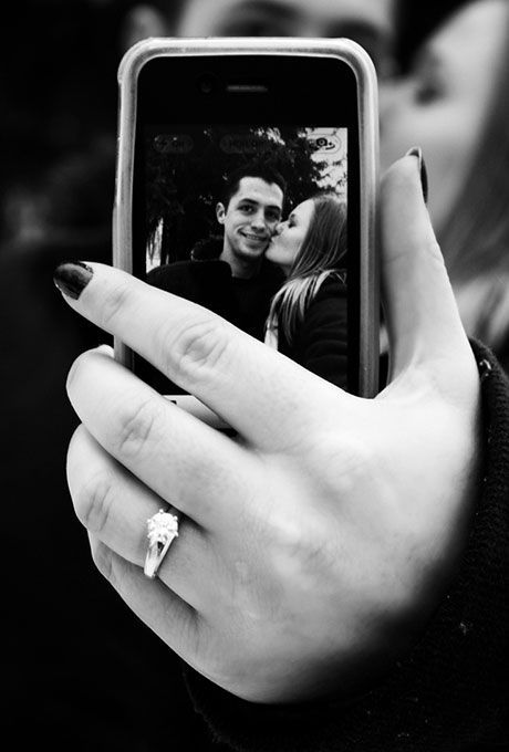 a person holding up a cell phone to take a photo with their engagement ring on it