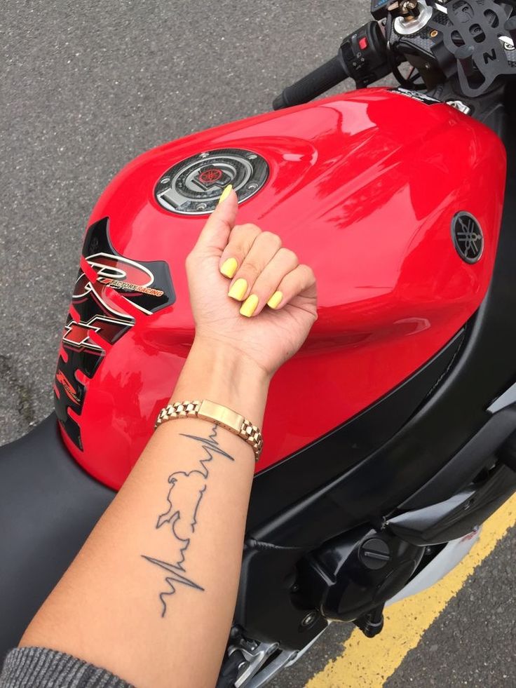 a woman's hand on the handle bar of a red motorcycle