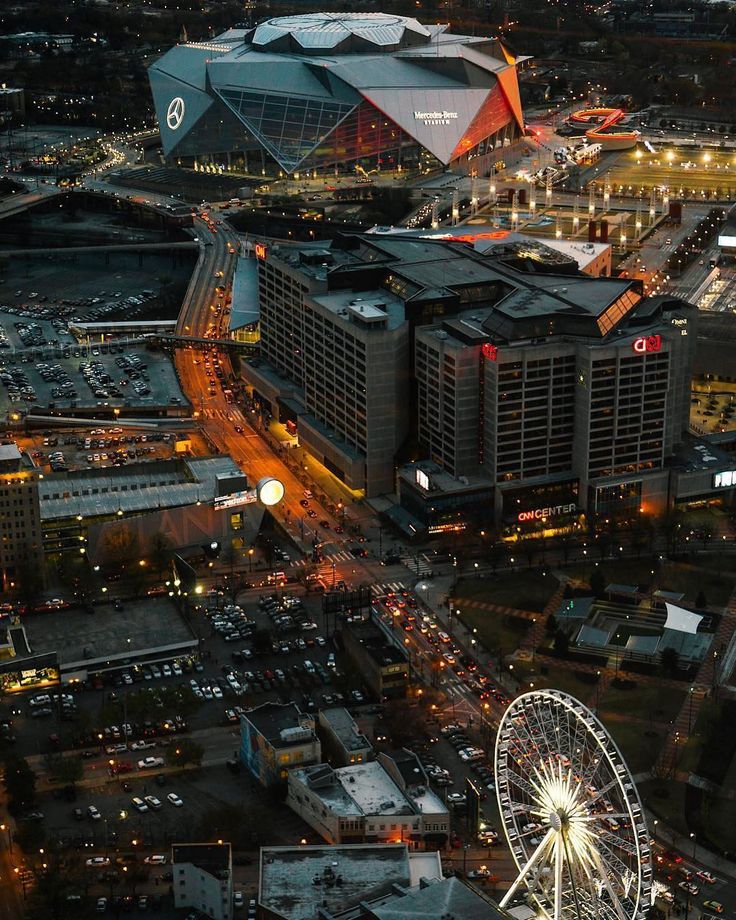 an aerial view of a city at night with the ferris wheel in the foreground