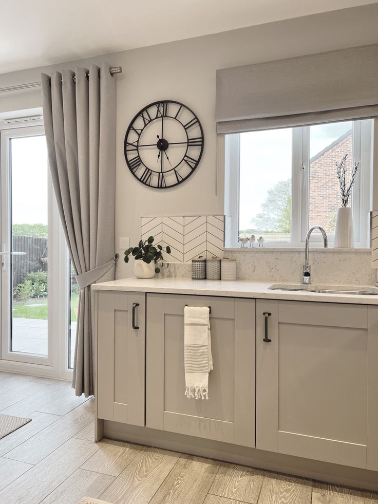 a kitchen with a large clock on the wall above it's sink and window