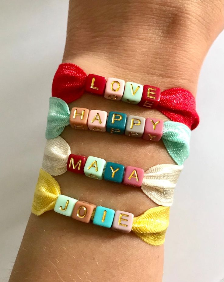 three bracelets that say love, happy, and may be made with letters on them