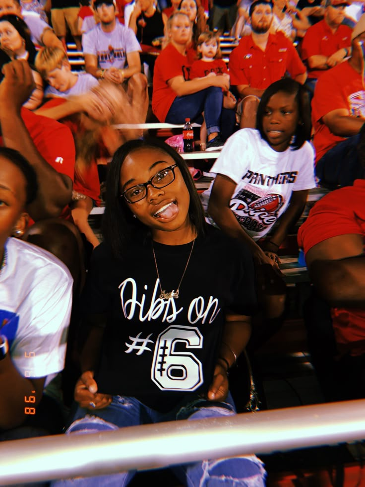 two women are sitting in the stands at a basketball game and one woman is smiling