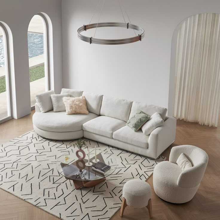 a living room filled with white furniture and large arched windows overlooking the water in front of it