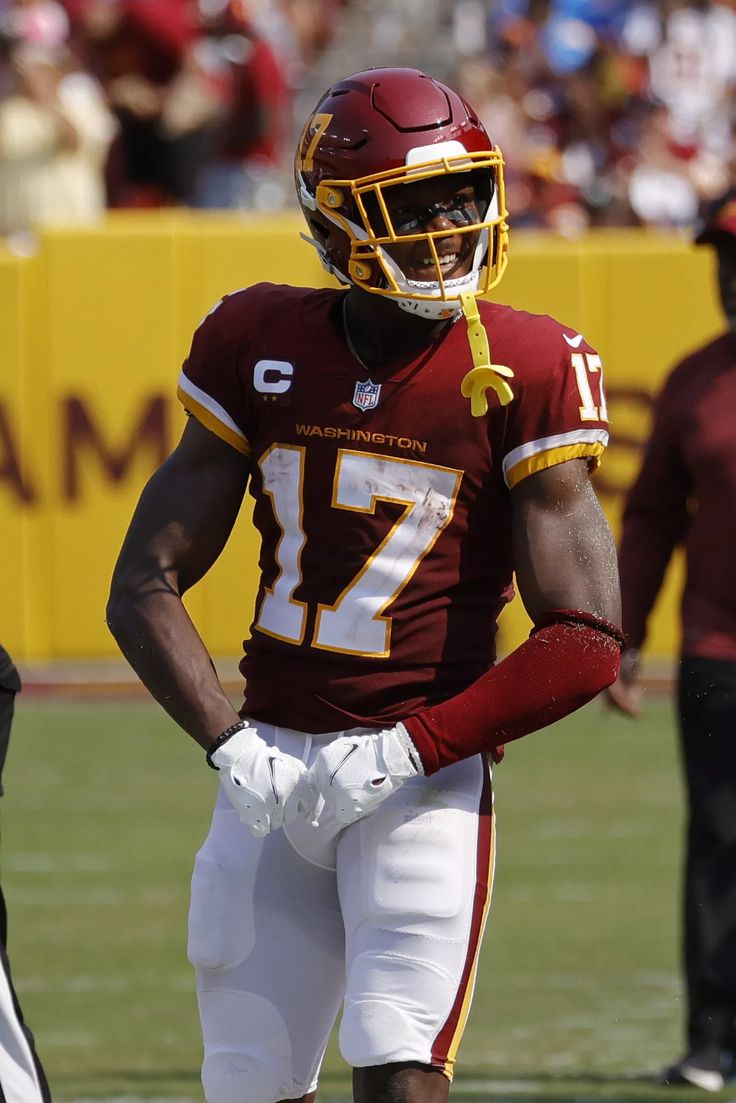 a football player standing on the field with his hands in his pockets and wearing a helmet