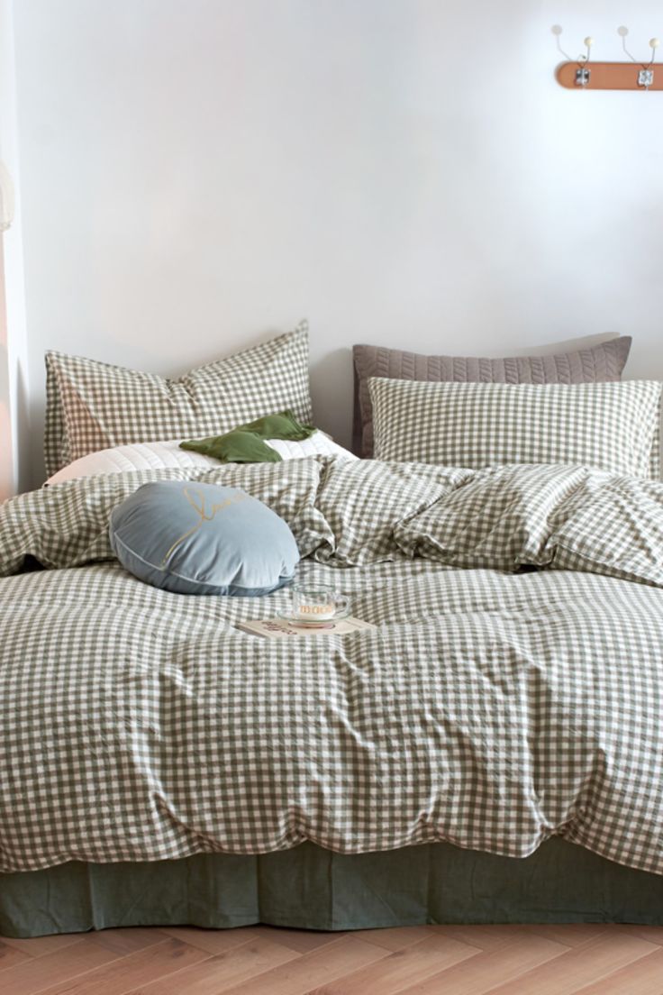 an unmade bed with pillows and blankets on it in a room that has wooden floors